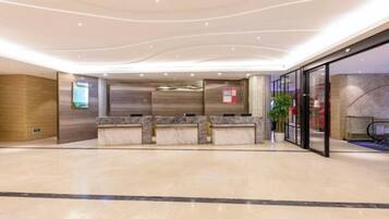 A spacious lobby with a reception desk, marble flooring, and a glass wall.