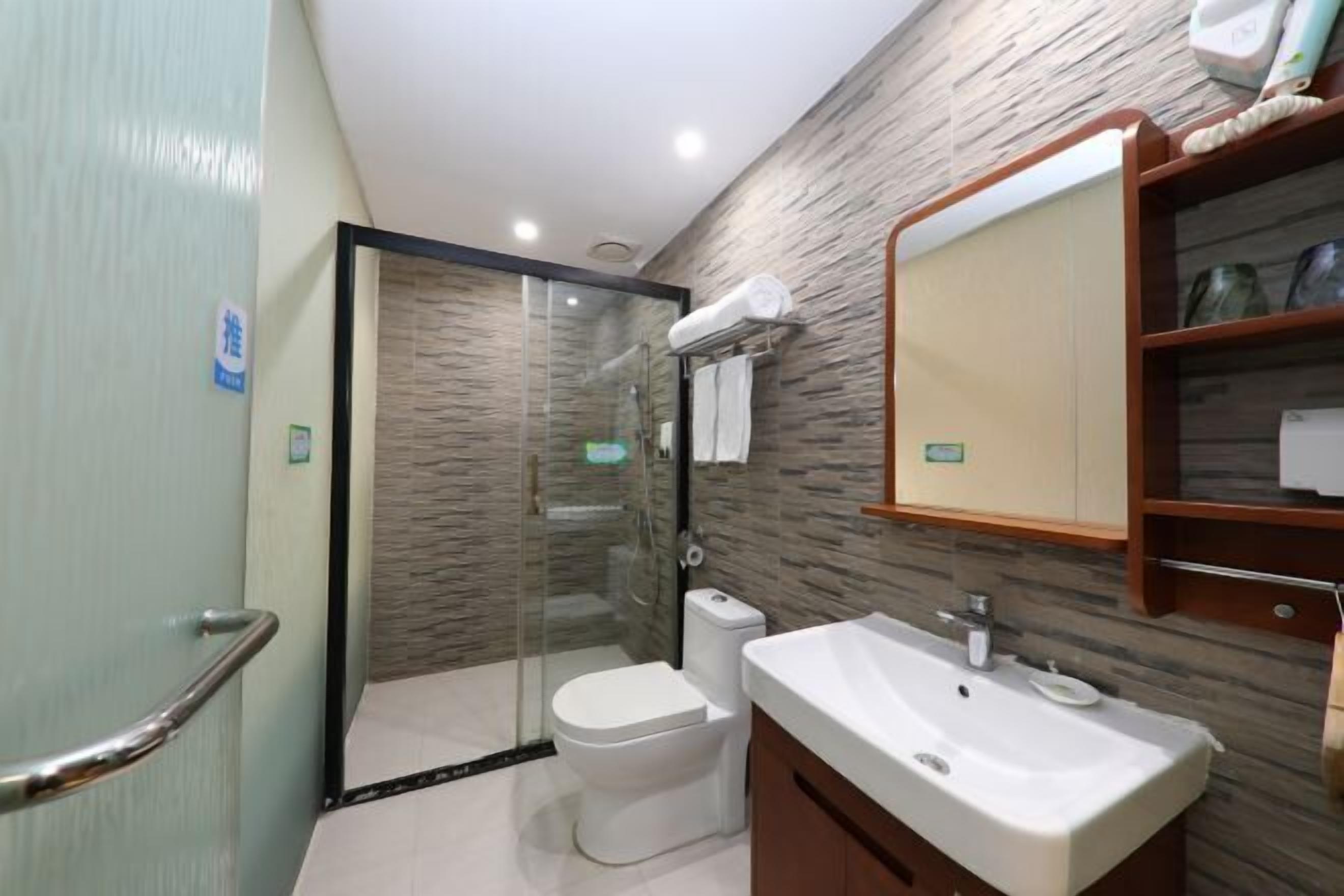 A modern bathroom with a glass-enclosed shower, a white toilet, and a sink with a mirror above.