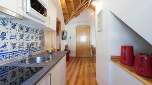 Een smalle keuken met een houten plafond, een betegelde spatwand en een houten vloer.