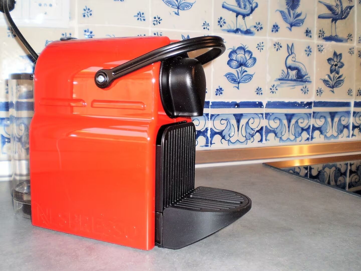 Une bouilloire électrique rouge, dotée d’une anse et d’un socle noirs, posée sur un plan de travail de cuisine.