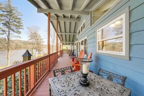 A covered porch with a table and chairs, overlooking a body of water and hills. - Mtn-View Home w/ Dock on Lake Glenville! (Cullowhee)