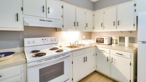 A kitchen with white cabinets, a stove, a microwave, and a sink. - Walk to Eats & Entertainment: Home in Brookhaven (Brookhaven)