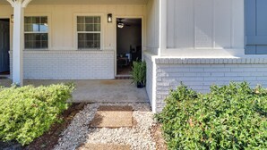 A house with a white exterior, a covered porch, and a gravel pathway leading to the entrance. - Walk to Eats & Entertainment: Home in Brookhaven (Brookhaven)