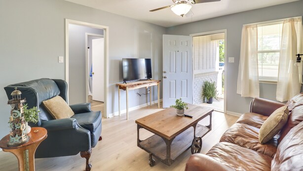 A living room with a dark leather sofa, a wooden coffee table, a television on a stand, and a ceiling fan. - Walk to Eats & Entertainment: Home in Brookhaven (Brookhaven)