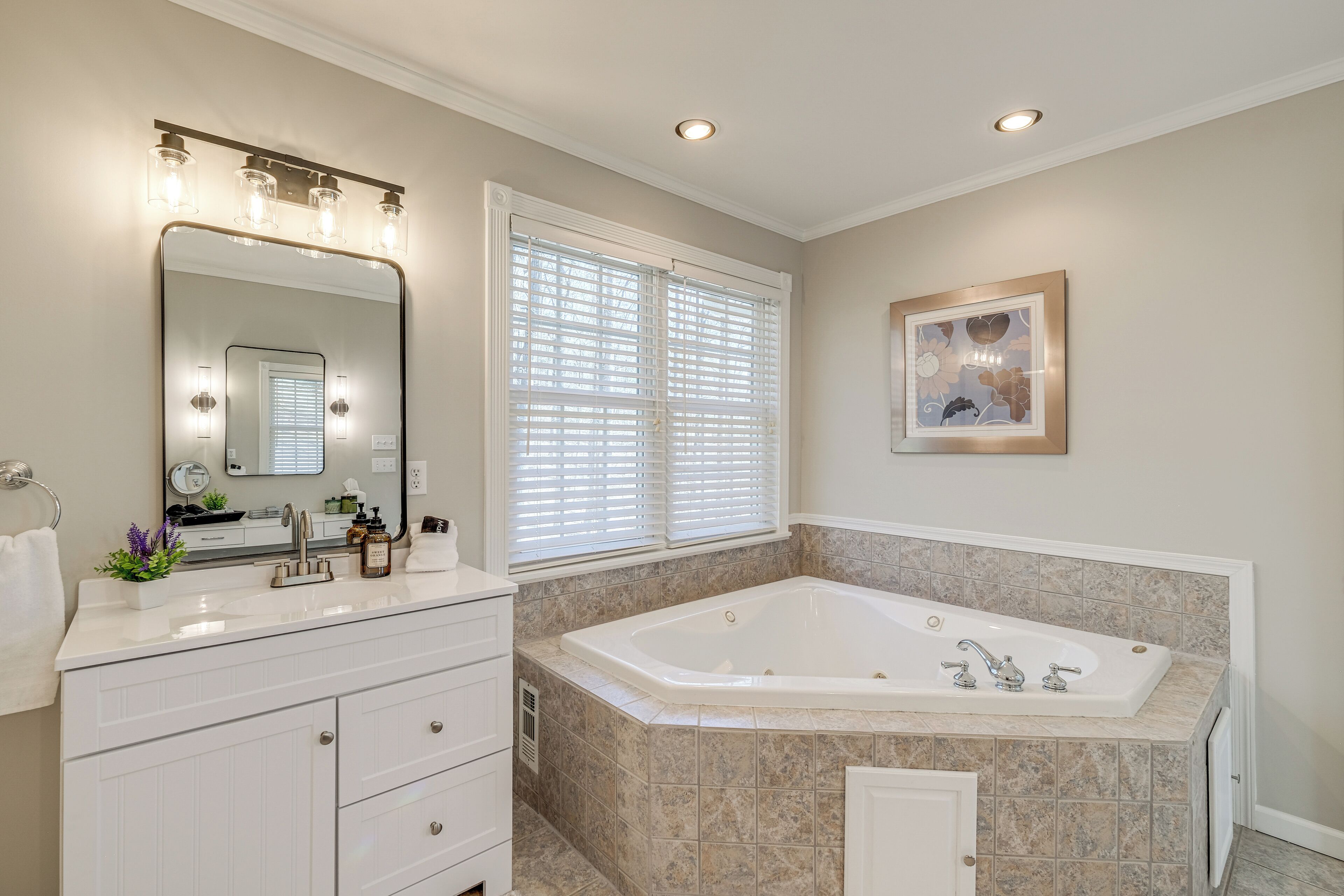 A bathroom with a large mirror, vanity, and a freestanding bathtub.