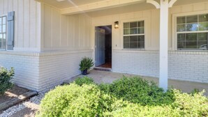 A white house with a covered porch, a door, and a window. - Walk to Dining & Shops: Dtwn Brookhaven Home! (Brookhaven)