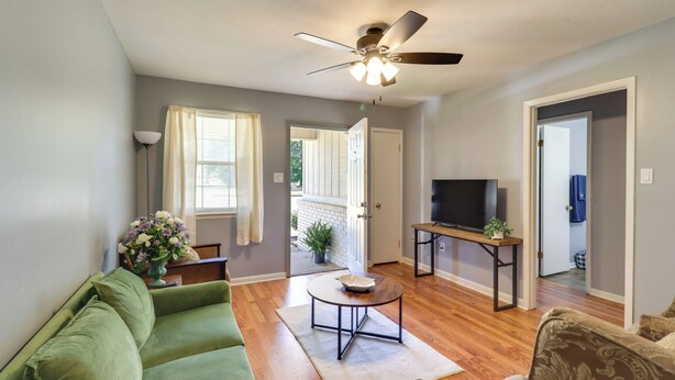 A living room with a green sofa, a coffee table, a ceiling fan, and a TV. - Walk to Dining & Shops: Dtwn Brookhaven Home! (Brookhaven)