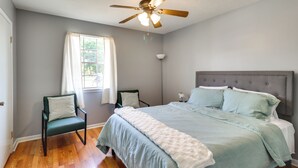 A bedroom with a bed, two chairs, a ceiling fan, and a window with curtains. - Walk to Dining & Shops: Dtwn Brookhaven Home! (Brookhaven)