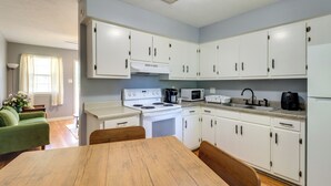A kitchen with white cabinets, a stove, a microwave, and a sink. There is a dining table with chairs. - Walk to Dining & Shops: Dtwn Brookhaven Home! (Brookhaven)