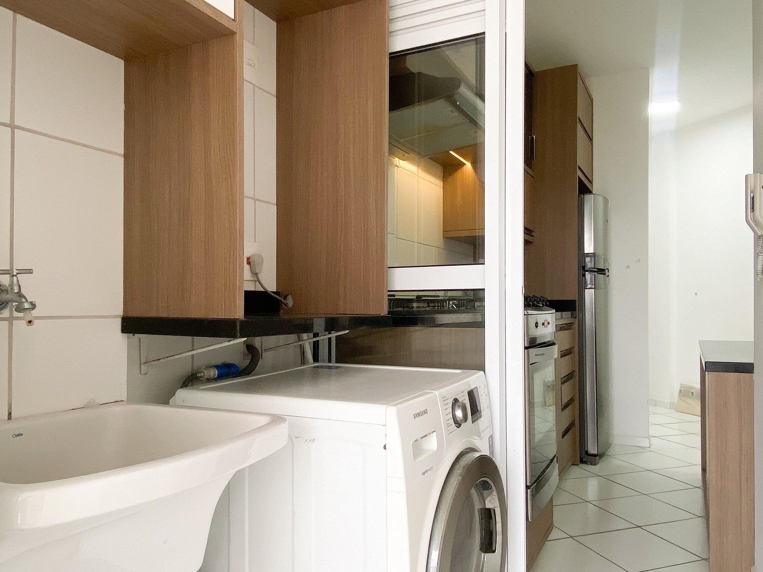 A compact kitchen with a washing machine, a sink, and a refrigerator.
