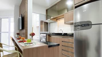 Cuina moderna amb armaris de fusta, un frigorífic d'acer inoxidable i una zona de menjador amb cadires de vimet.