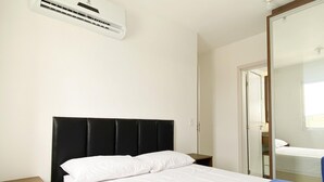 A hotel room with a bed, a nightstand, a mirror, and an air conditioning unit. - Resid. Clube Mar Grosso-Laguna - LAG504 (Laguna)