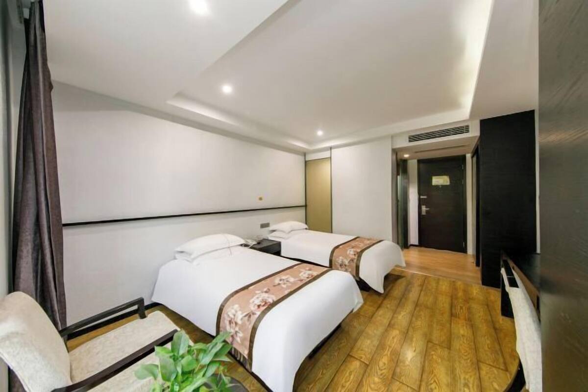 A hotel room with two beds, a TV, a desk, and a chair.