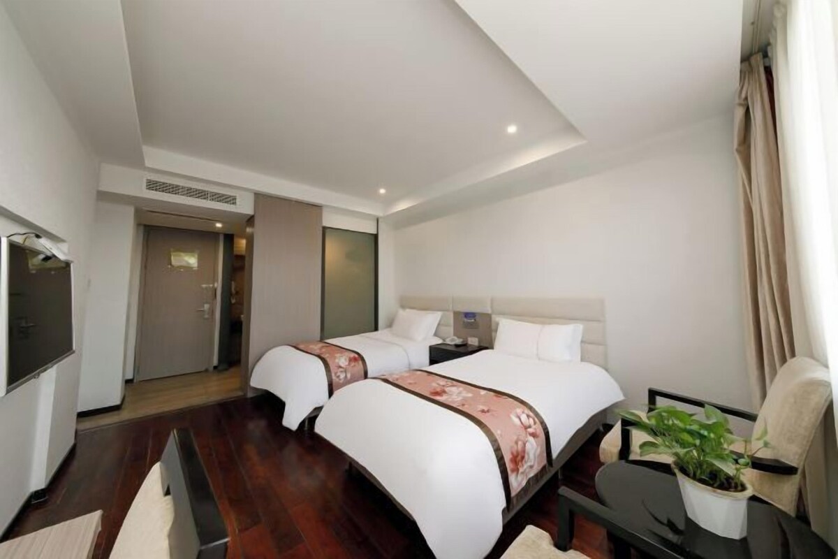 Una habitación de hotel con dos camas, televisión, escritorio y una silla.