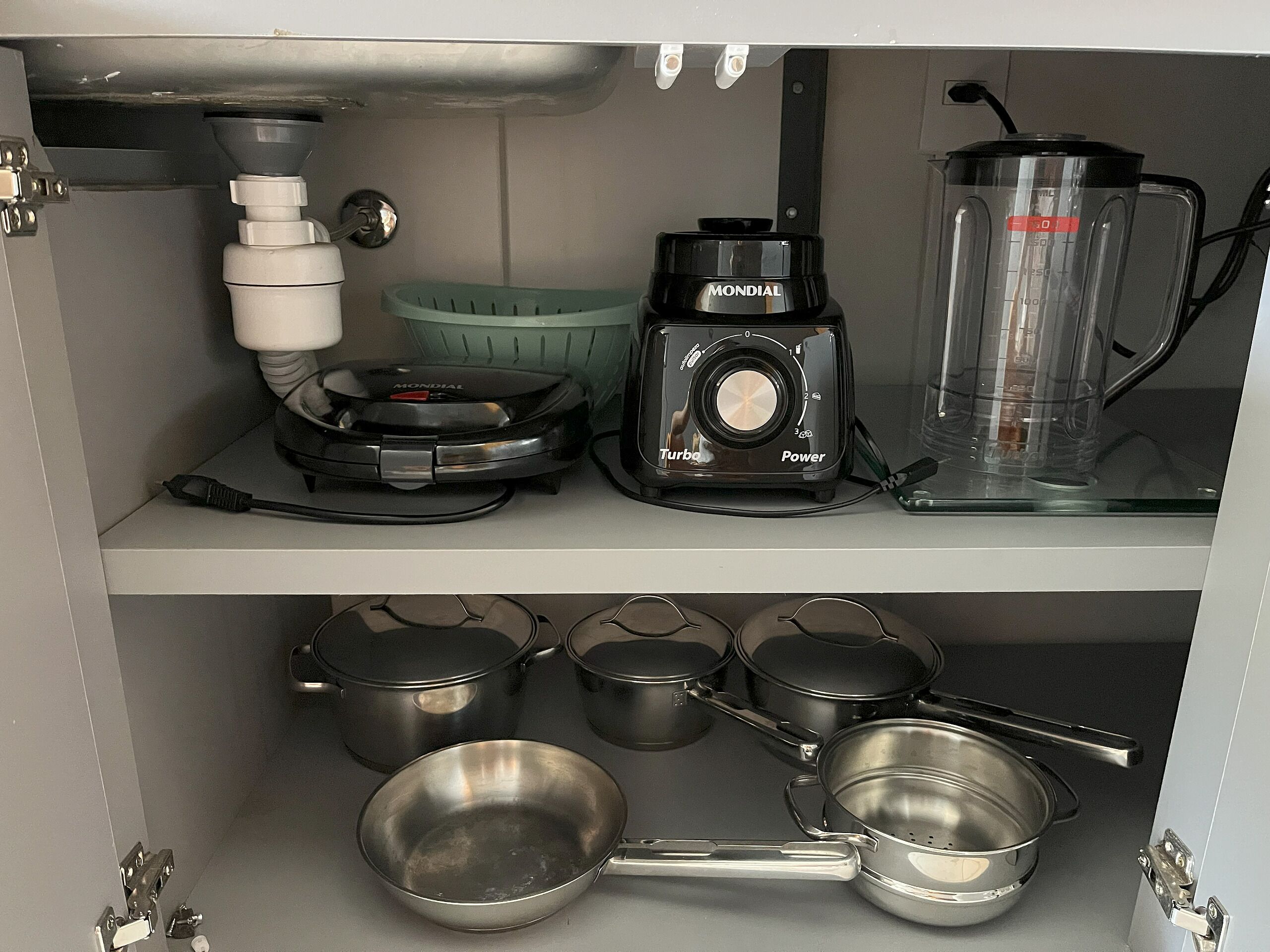 Une cuisine équipée d’une machine à café, d’un mixeur et de différents ustensiles de cuisine, comme des casseroles et des poêles.