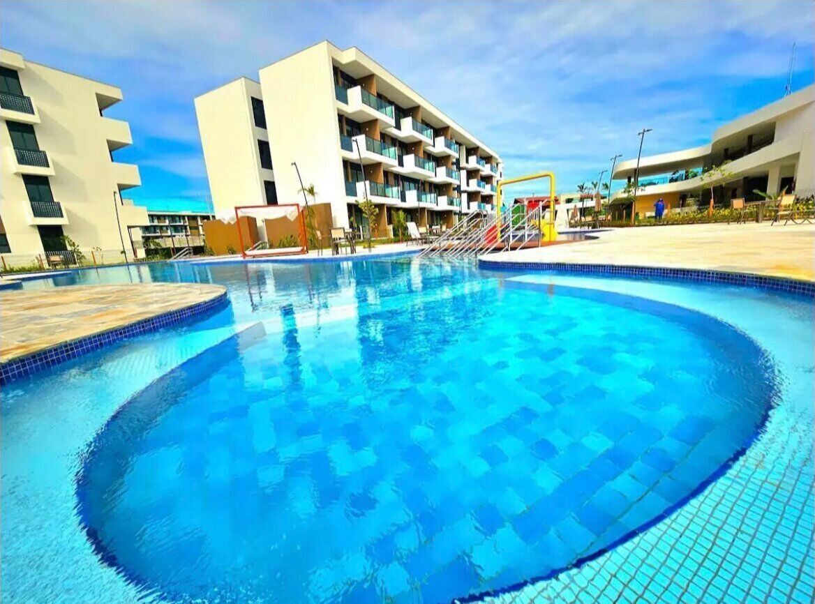 Una piscina con bordo piastrellato, circondata da edifici moderni con balconi.