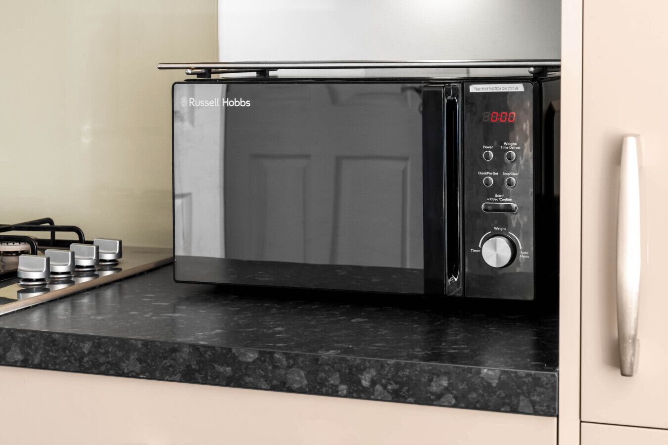 A modern kitchen with a built-in microwave oven, a gas stove, and a stainless steel range hood.