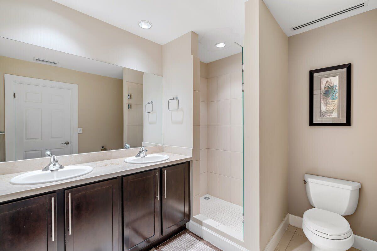 Un baño moderno con lavamanos doble, cabina de ducha de cristal y un inodoro.