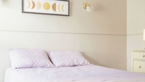 A bedroom with a bed, a wall-mounted picture of moon phases, and a nightstand.