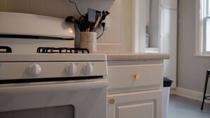 A kitchen with a white stove, a countertop, and a cabinet above it.