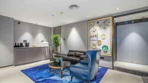 En moderne stue med sofa, blå lænestol, sofabord og en dekorativ vægdekoration.