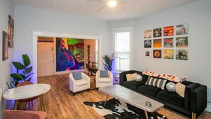 A modern living room with a black sofa, white armchairs, a coffee table, and a large abstract painting on the wall. - Neon Nashville! 5 min to Broadway •Walk 2 dining! (Nashville)