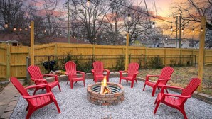 A backyard with a fire pit surrounded by red chairs, a yellow fence, and string lights. - Neon Nashville! 5 min to Broadway •Walk 2 dining! (Nashville)