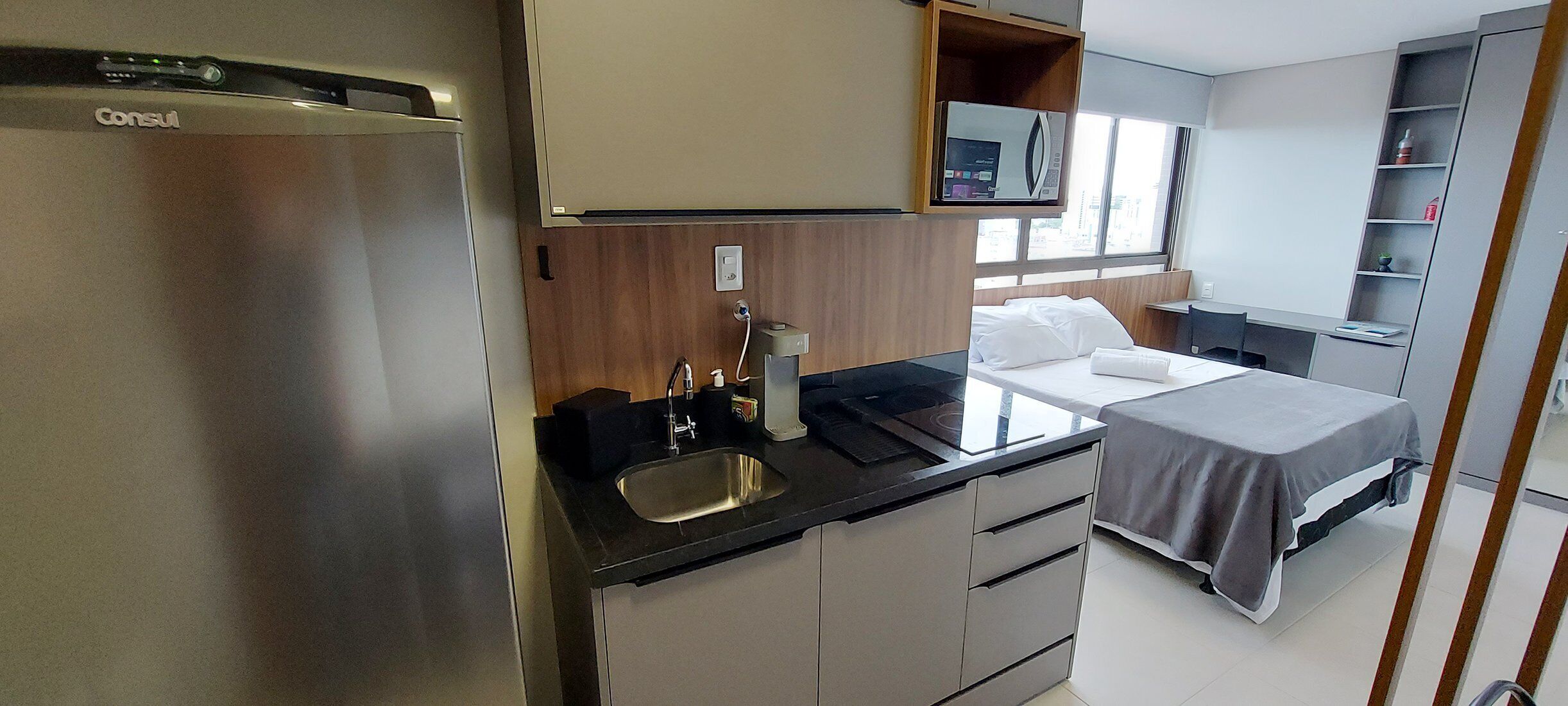 A compact kitchenette with a refrigerator, sink, and countertop.