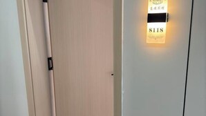 Entrada a una habitación de hotel con una puerta de madera y un letrero iluminado con el número de habitación.