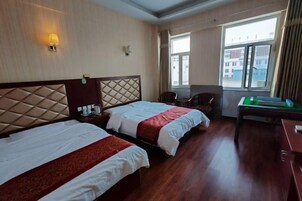 Habitación de hotel con dos camas, un escritorio, una silla y una ventana con vistas a edificios.