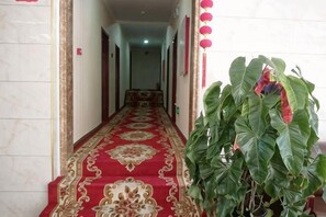 A hallway with a red carpet, a plant, and red lanterns. - Damaoqi Haode Business Hotel (Damao Banner)