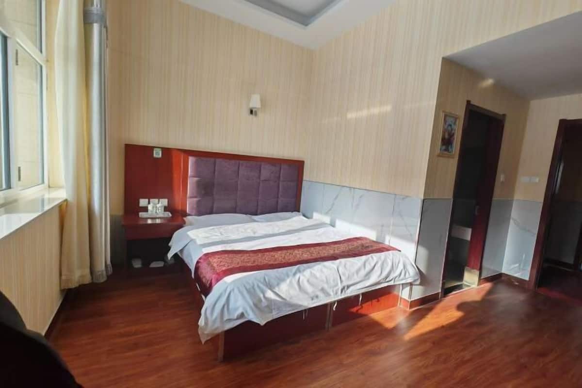 Una habitación de hotel con cama, mesita de noche y ventana.