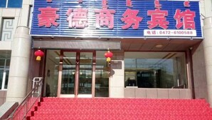 Entrada de hotel con alfombra roja, puertas de cristal y faroles rojos.