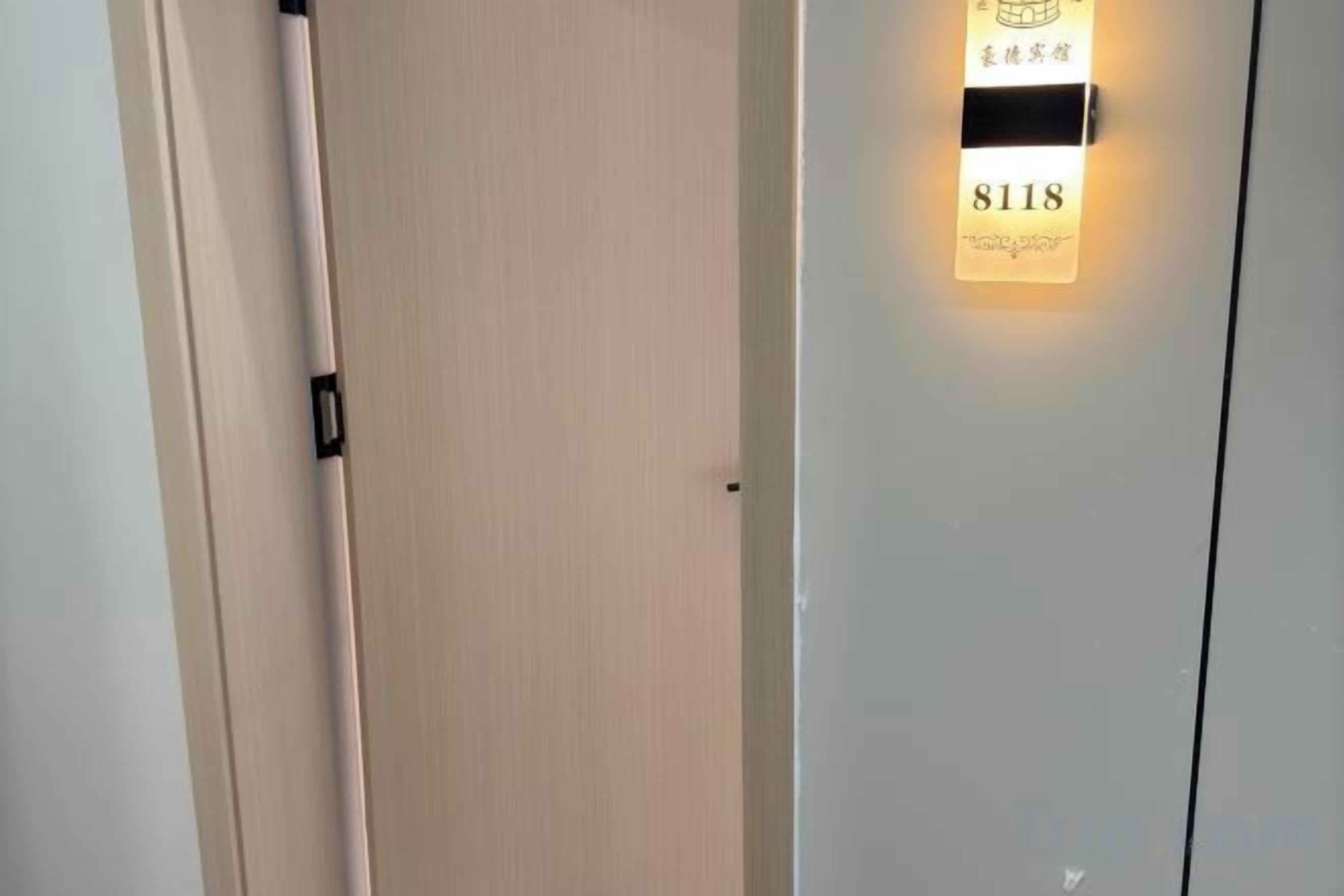 A door with a lighted sign above it, displaying the number 8118.