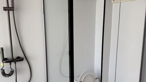 Un baño con inodoro, ducha y perchero.