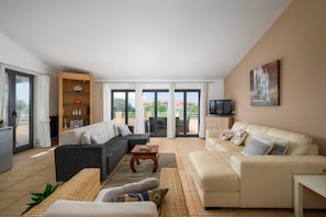 A living room with a sofa set, a coffee table, and a television. There is a sliding glass door leading to an outdoor area. - Apartment Panous 3 (Stranici kod Nove Vasi)