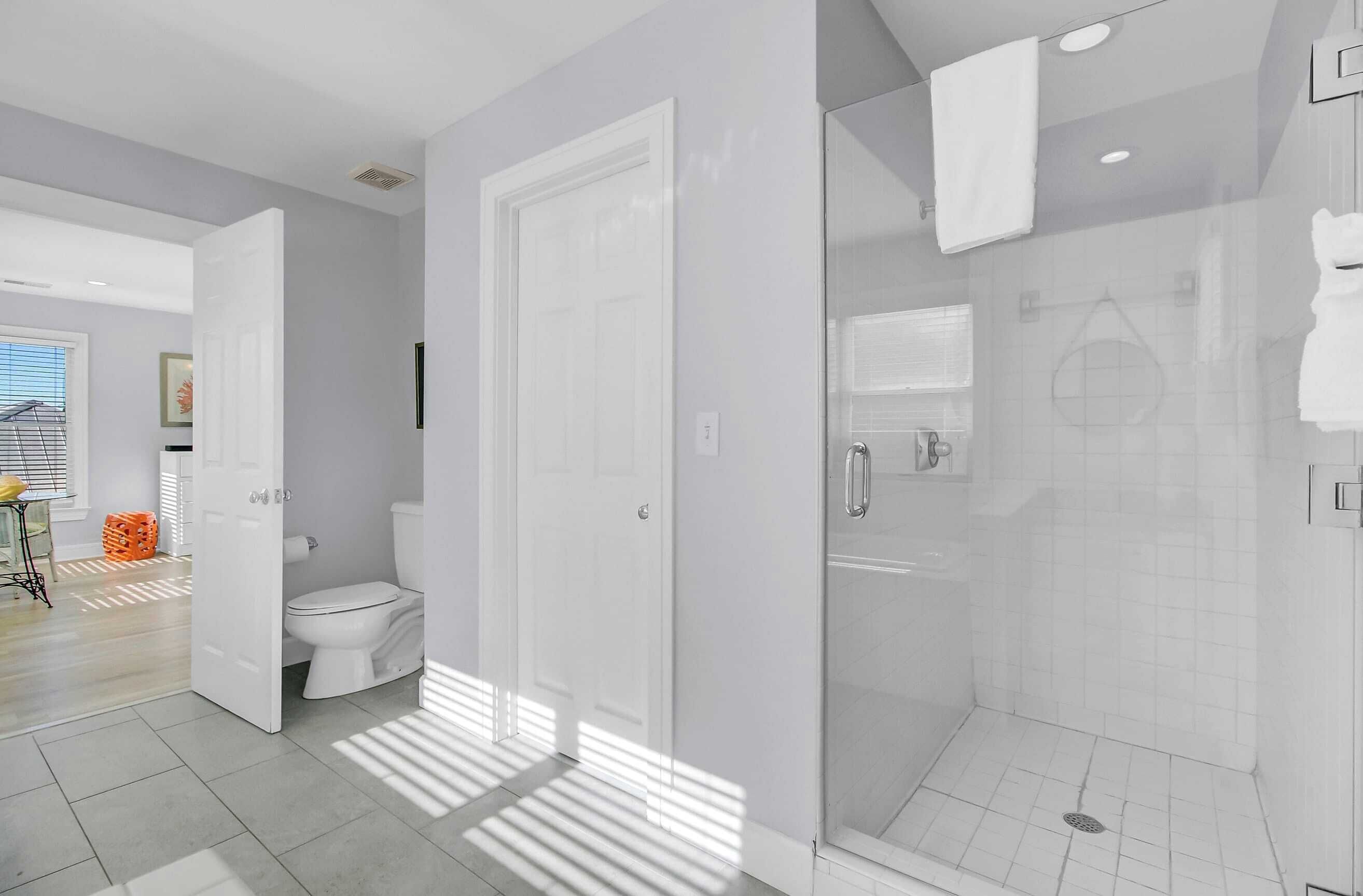 A modern bathroom with a toilet, shower, and glass-enclosed shower area.