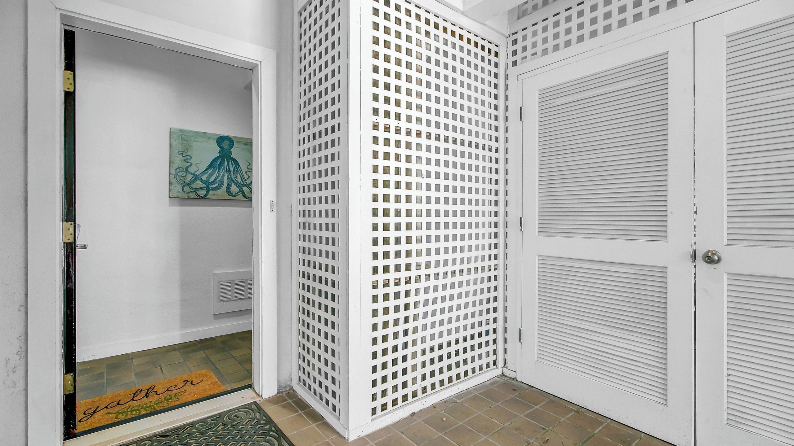 A hallway with a white door, a door with a grid pattern, and a door with horizontal blinds.