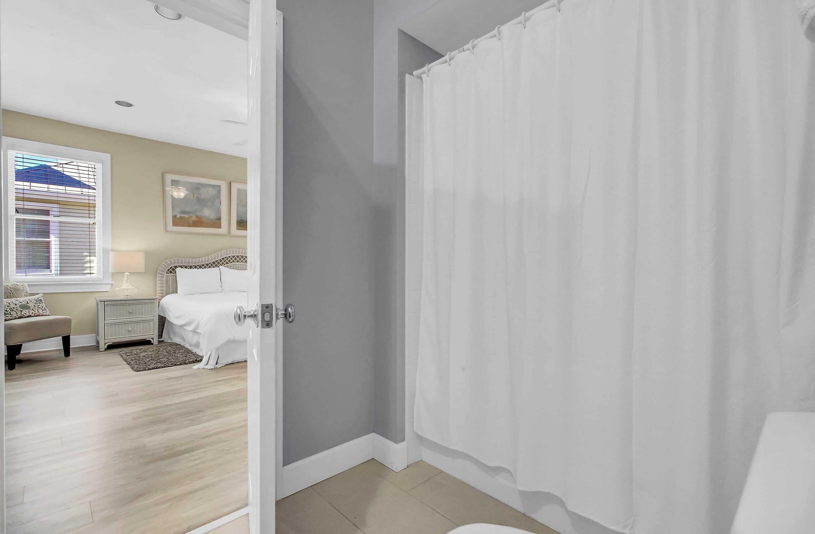 A bedroom with a bed, bedside table, lamp, and a window with blinds.