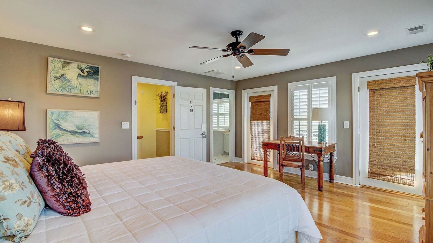 A bedroom with a bed, a ceiling fan, a desk, and a chair.