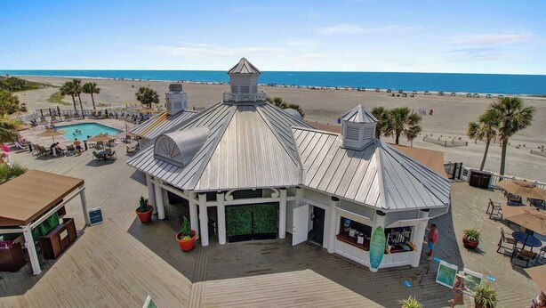 A beachside building with a pool, outdoor seating, and a view of the ocean.