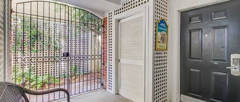 A gated entrance with a metal gate, a closed white door with a keypad lock, and a bench outside.