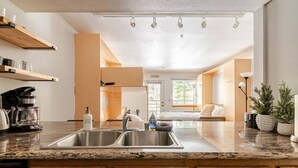 Una cocina moderna con un lavamanos doble, armarios de madera y una cafetera.