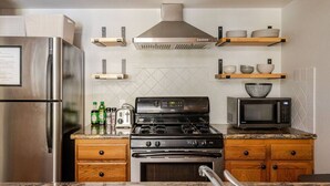 Una cocina moderna con electrodomésticos de acero inoxidable, armarios de madera y un microondas en la encimera.