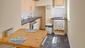 Una cucina funzionale con tavolo in legno, lavello, fornello e cestino.