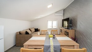 A compact living space with a dining table, sofa, and TV. - Beautiful apartment in Gornji Karin with WiFi (Gornji Karin)