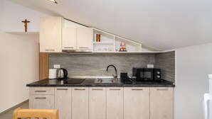 A modern kitchen with light wood cabinets, a black countertop, a sink, a kettle, a coffee maker, and a microwave. - Beautiful apartment in Gornji Karin with WiFi (Gornji Karin)