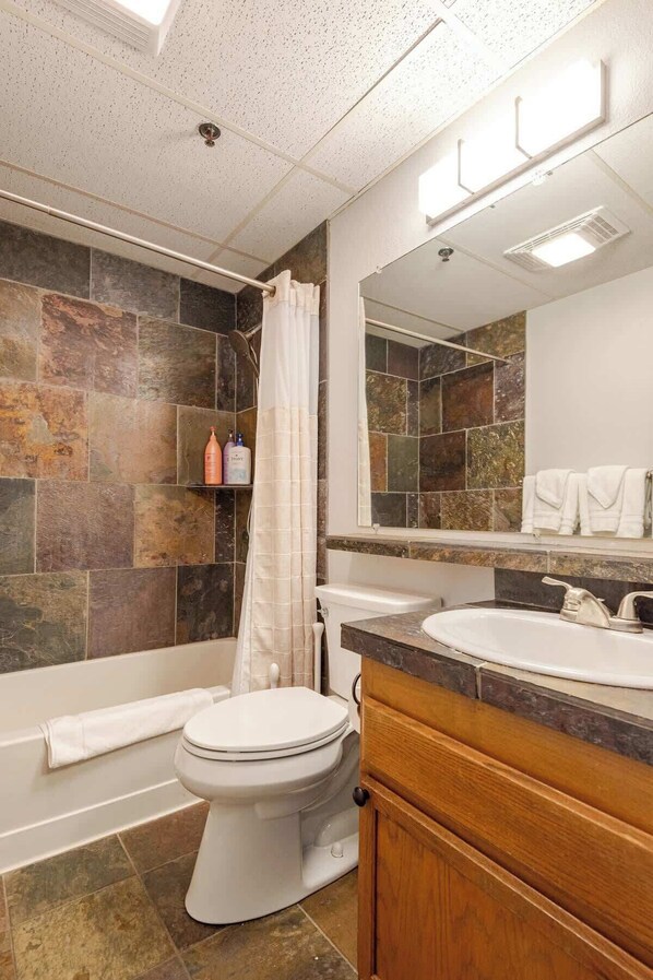 A bathroom with a shower, toilet, and sink.