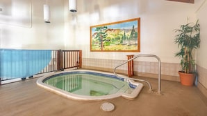 Una piscina interior con cubierta de madera, un cuadro en la pared y una planta en maceta.