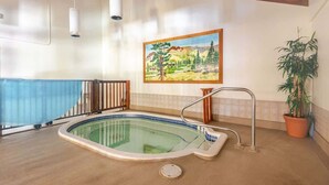 Una piscina interior con cubierta de madera, un cuadro en la pared y una planta en maceta.